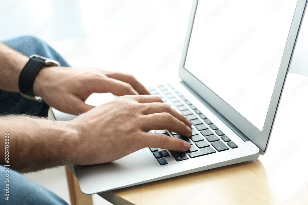 Man working on modern laptop at wooden table indoors, closeup Man working on modern laptop at wooden table indoors, closeup