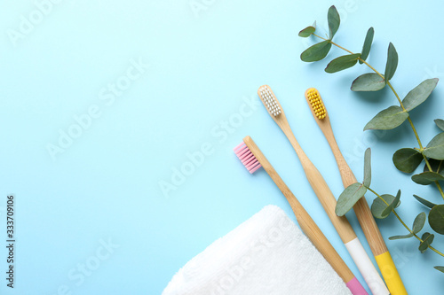 Flat lay composition with toothbrushes made of bamboo on light blue background. Space for text