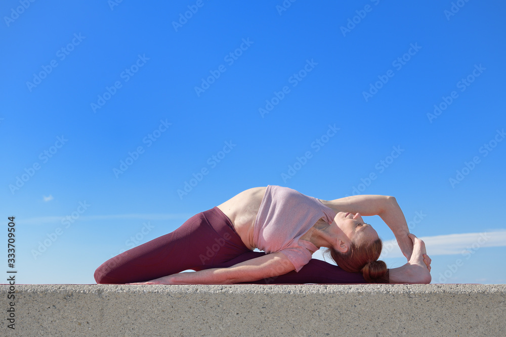 Portrait of a fit woman who practices yoga outdoors. Woman practicing asanas on a sunny day