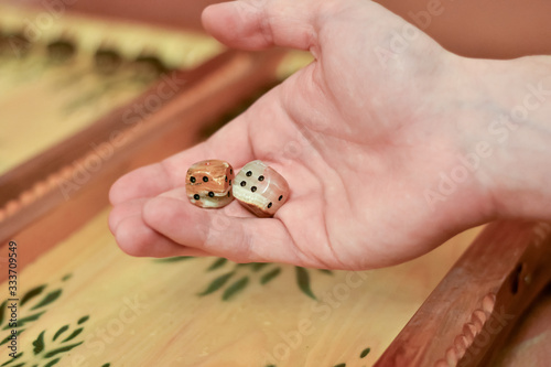 A hand holding white dice over a backgammon Board. The concept home games. photo