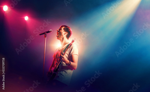 Singer with a guitar performing on a stage © TandemBranding
