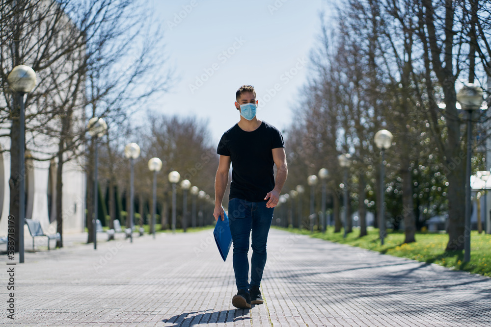 Caucasian male in medical masks walking in a city park. The concept of Coronavirus