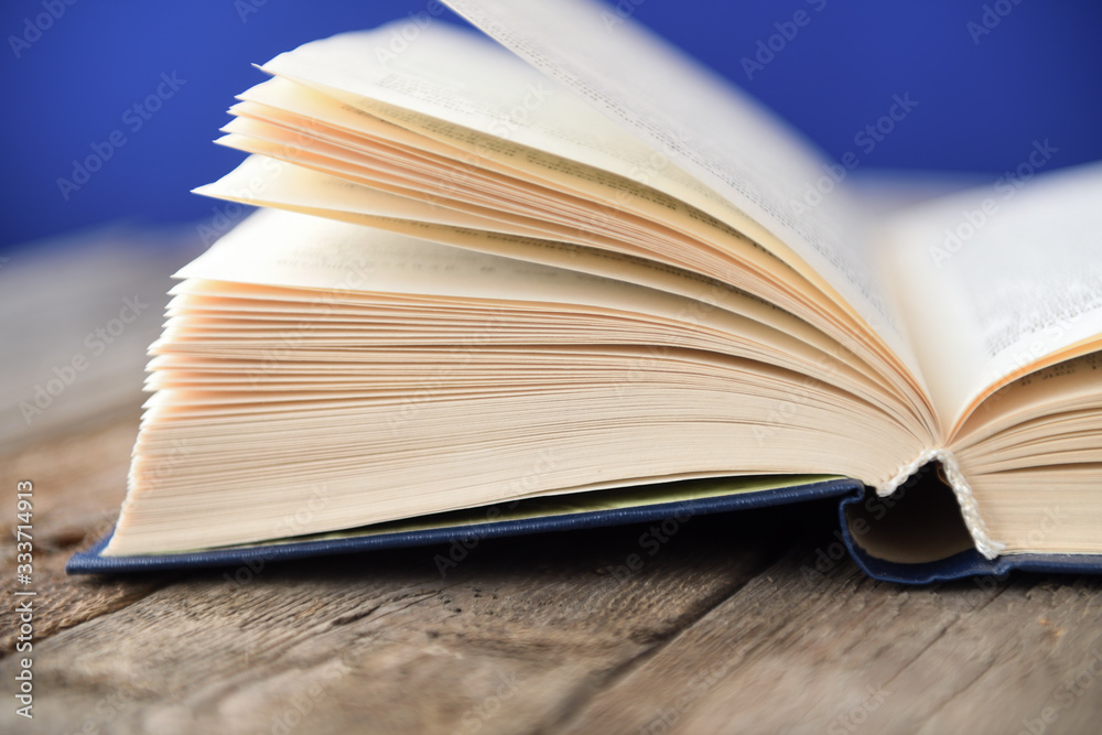 An open book on an old wooden table on a blue background. An open book on an old wooden table on a blue background.