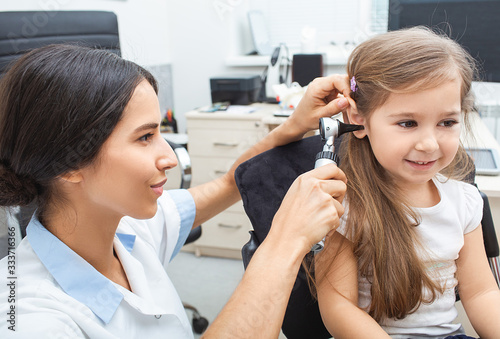 Audiologist examining little patient with otoscope, hearing exam of child