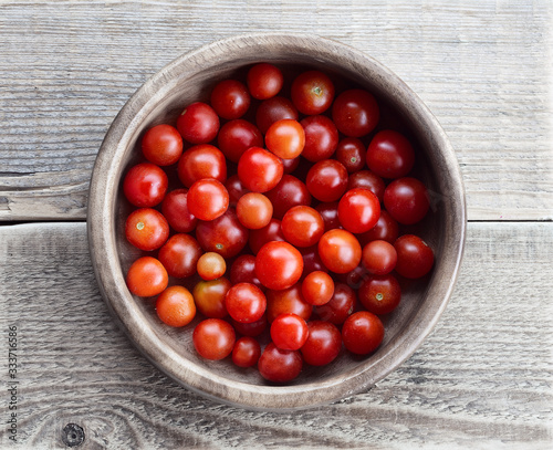 Tomatoes in a wooden bowl. Cherry tomatoes in a bowl on the table. Fresh harvest from the garden. Top view