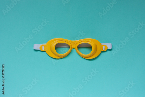 Children's protective yellow glasses on aquamarine background. Isolate. space for text.
