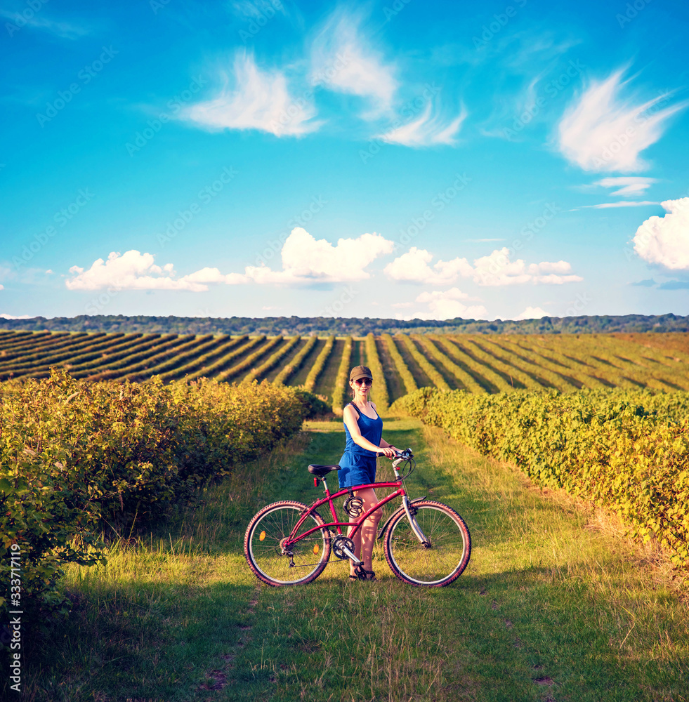 Carefree smiling girl cycling alone in a field among currant bushes in the garden. the best solution to escape from a coronavirus