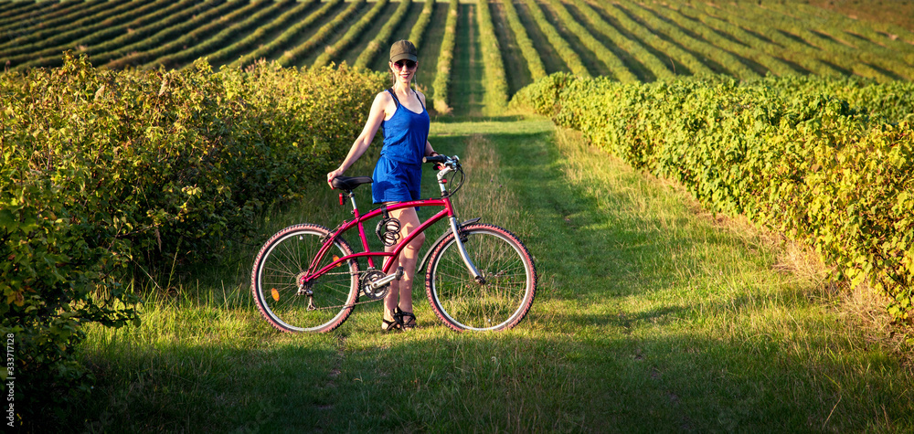 Carefree smiling girl cycling alone in a field among currant bushes in the garden. the best solution to escape from a coronavirus