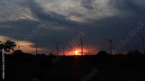 Wind turbines spin against the backdrop of the hot setting sun