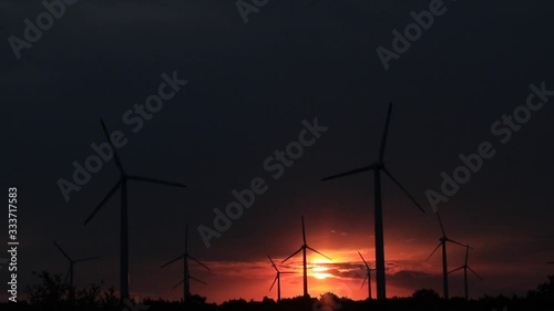 Wind turbines spin against the backdrop of the hot setting sun
