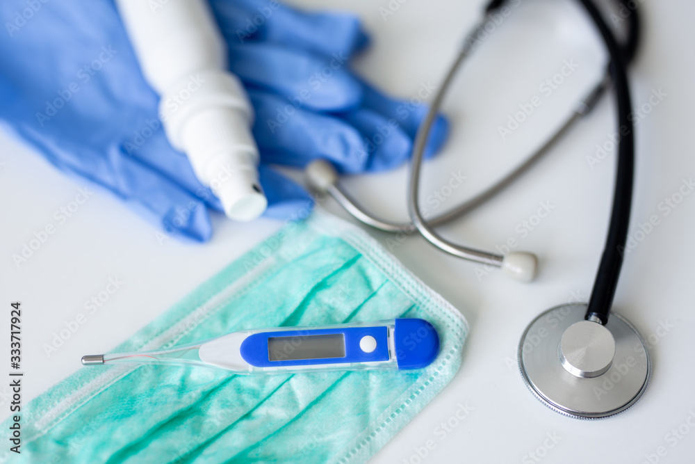 medicine, health care and pandemic concept - stethoscope, protective mask, gloves, sanitizer and thermometer over white background medicine, health care and pandemic concept - stethoscope, protective mask, gloves, sanitizer and thermometer over white background