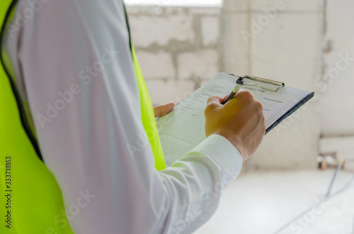 Obraz na płótnie foreman builder, engineer or inspector in green safety vest reflective checking