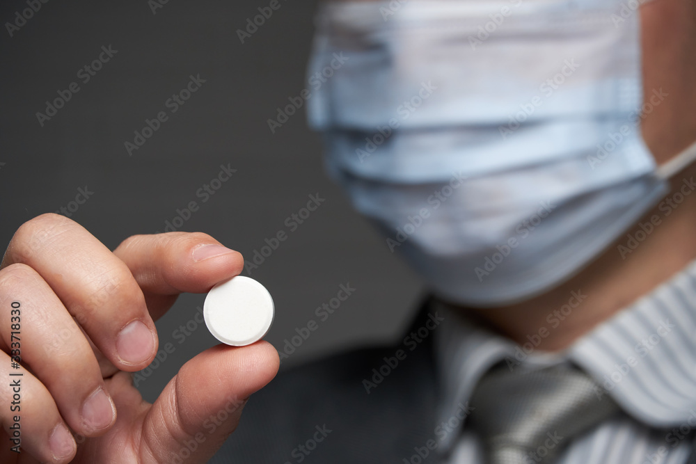 a man with a mask on his face for antivirus individual protection showing a pill - healthcare and medicine concept, prevention tips