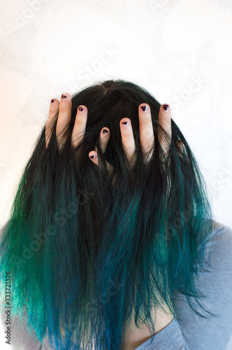 A portrait of unrecognizable young woman with green hair and her arms in her hair