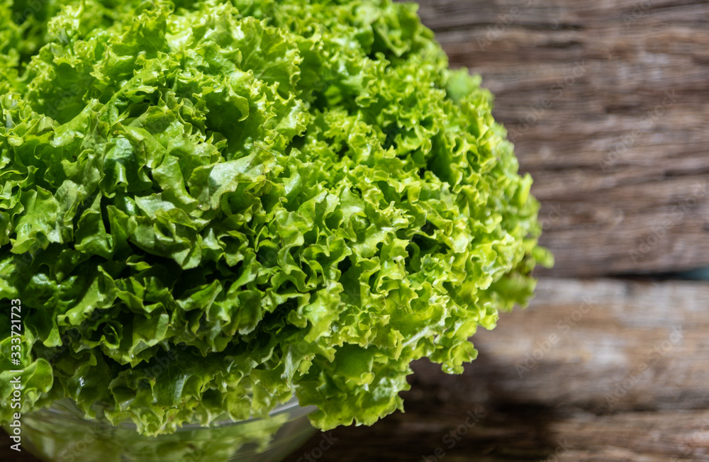 Lettuce (Lactuca sativa) in glass bowl and woody background Lettuce (Lactuca sativa) in glass bowl and woody background