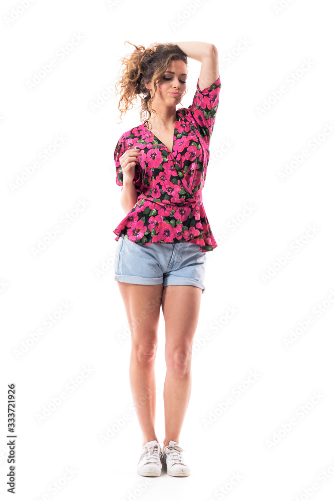 Fototapeta premium Cocky attitude confident sexy young woman holding hair in bun looking down and thinking. Full body isolated on white background. 