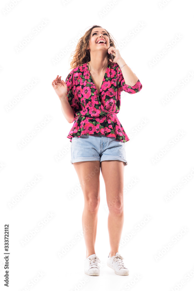 Laughing joyful young woman in summer clothes talking on the cellphone looking up. Full body isolated on white background. Laughing joyful young woman in summer clothes talking on the cellphone looking up. Full body isolated on white background.
