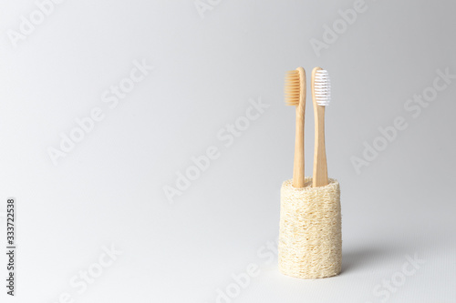 Two toothbrushes made of natural wood are inserted into the natural ecological loofah. on white background.