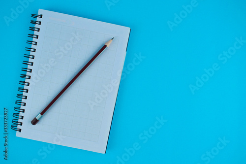 Purple pencil on top of a white opened diary before a light blue background