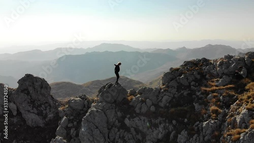 Aerial panoram view of girl walk on a mountain ridge. Beautiful view of the peaked tops of Durmitor in Montenegro