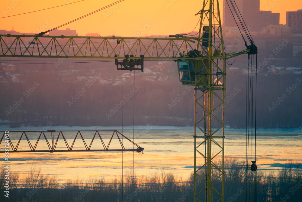 Cunstruction crane on the river sunset background