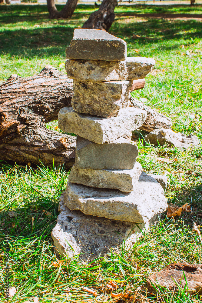 Fototapeta premium The stones lie rug on each other. A pillar of stones. Stone post on the grass.
