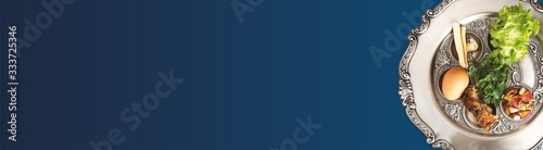 Pesach plate on a dark blue background, wide banner with a copyspace. Traditional Jewish seder on the occasion of Passover festival.