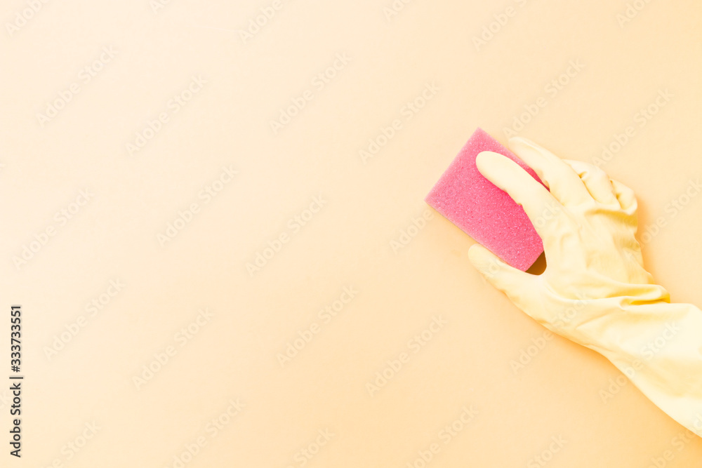 hand in a yellow rubber glove holds an orange sponge for washing dishes and cleaning, yellow background copy space, cleaning concept, home care, spring cleaning hand in a yellow rubber glove holds an orange sponge for washing dishes and cleaning, yellow background copy space, cleaning concept, home care, spring cleaning