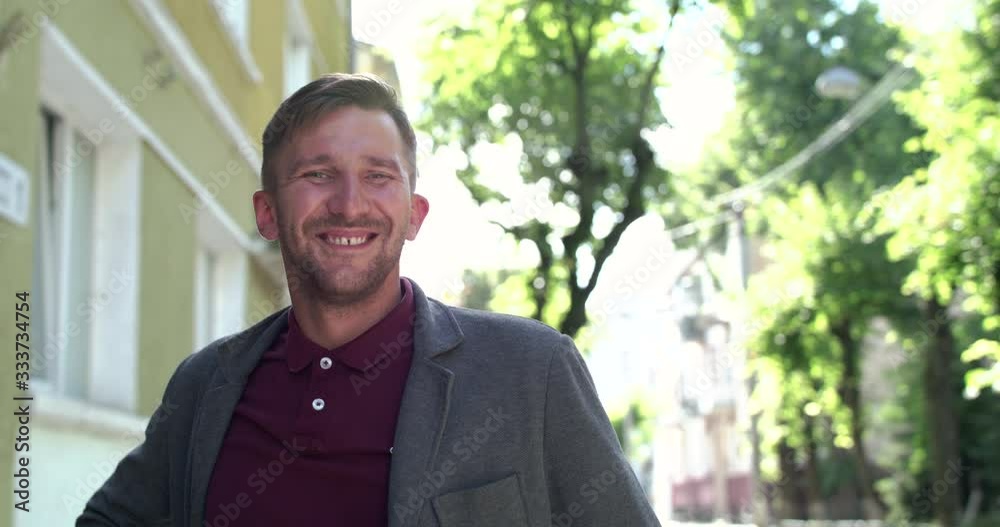 The charismatic man looking and smiling pleasantly at camera among on street The charismatic man looking and smiling pleasantly at camera among on street