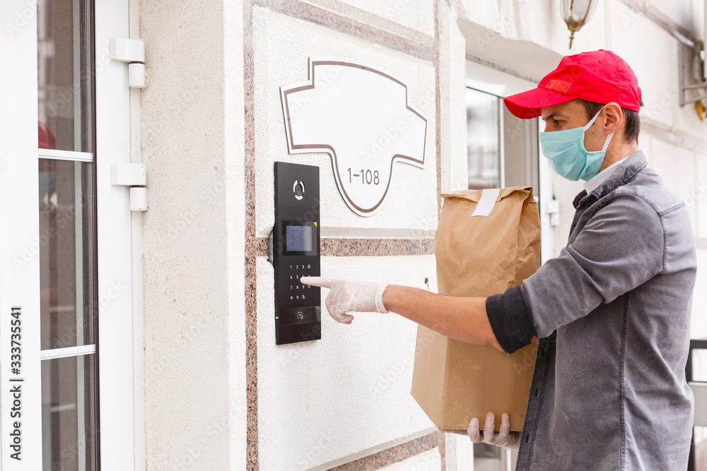 Courier's hands in latex white medical gloves deliver parcels in brown cardboard boxes to the door during the epidemic of coronovirus,COVID-19.Safe delivery of online orders during the epidemic.