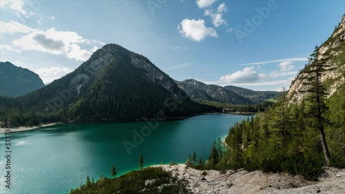 Braies lake seen from above on a slope of the mountain collapsed while the clouds move in the blue sky