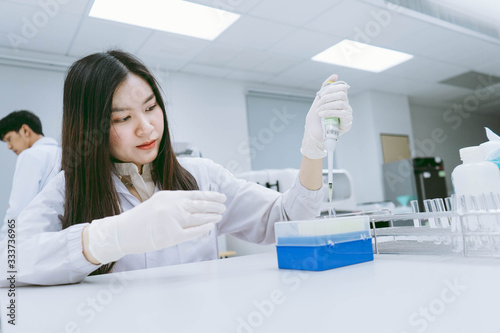 young medical  scientist working in medical laboratory   young female scientist  using auto pipette to transfer sample 