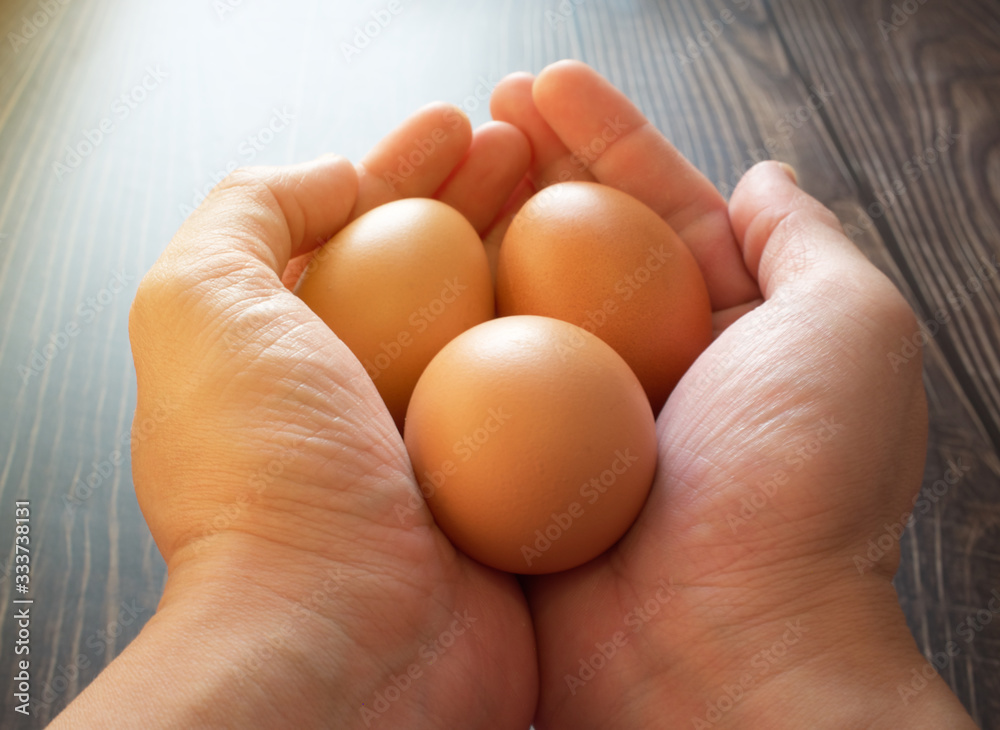 Asian man holding 3 eggs in hands with white light Asian man holding 3 eggs in hands with white light