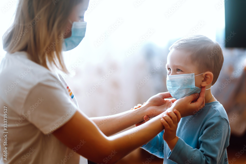 Little boy and mom in medical mask. Mother puts on her baby sterile