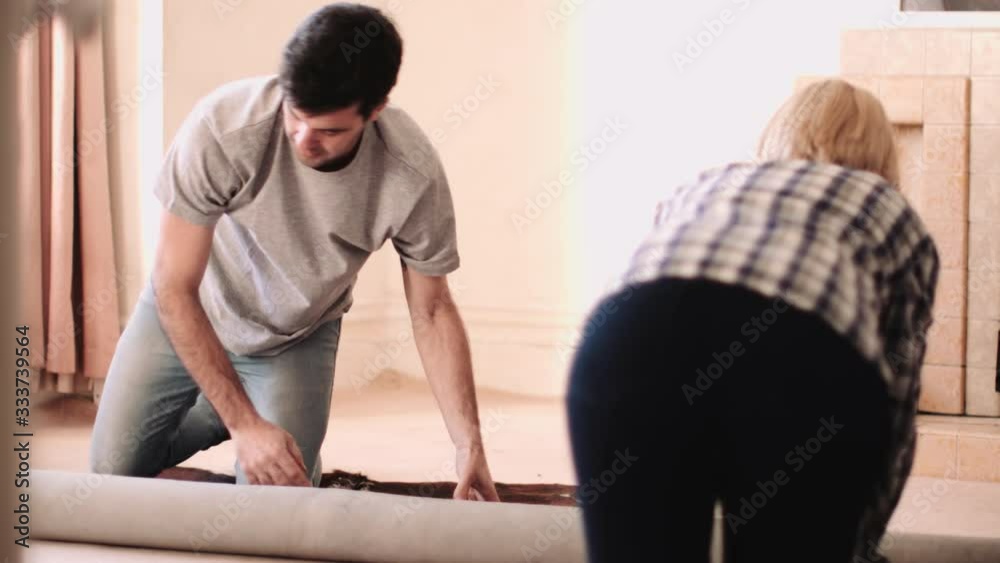 Adult Couple moving home and packing carpet Adult Couple moving home and packing carpet