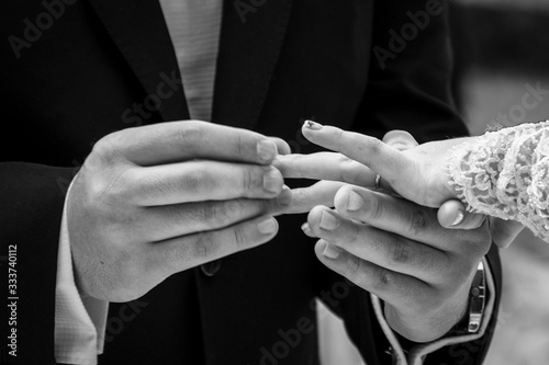 Fotograf  a mostrando las manos de los novios  cuando el novio coloca el anillo de bodas en el dedo anular de la novia durante la ceremonia de boda