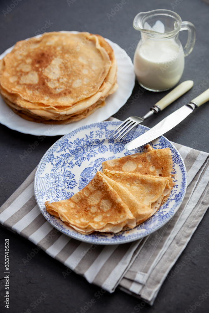A stack of thin pancakes on a plate. Homemade pastries. Pancakes for breakfast. Appetizing food. Thin pancakes on a plate. Homemade crepes, tasty food. Staple of yeast pancakes. A stack of thin pancakes on a plate. Homemade pastries. Pancakes for breakfast. Appetizing food. Thin pancakes on a plate. Homemade crepes, tasty food. Staple of yeast pancakes.