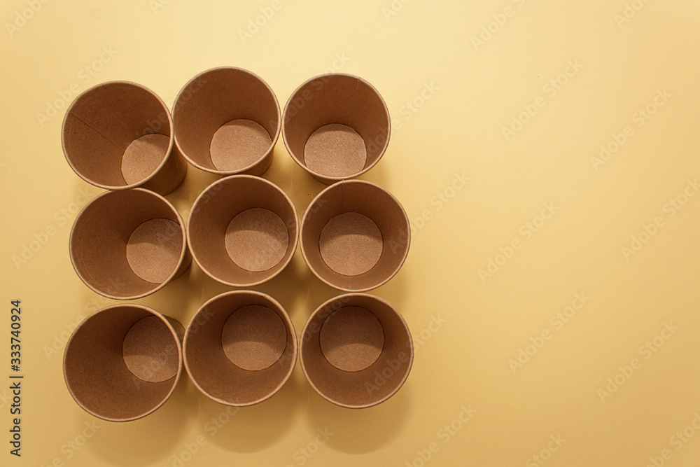 Many craft paper cups for coffee or any drinks on a yellow paper background. Concept of ziro waste, no plastic Many craft paper cups for coffee or any drinks on a yellow paper background. Concept of ziro waste, no plastic