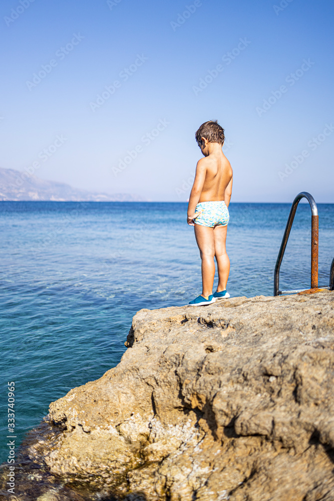 Little child looking the sea from a rocky coast