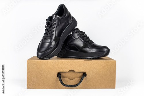 High quality leather demi-season black shoes stand on cardboard box for shoes on light background photo