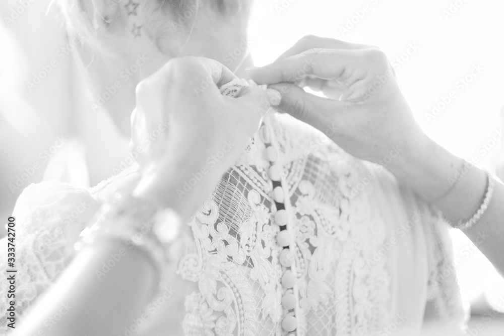 Bridesmaids tie ribbons on the back of the bride's dress. Bridesmaids tie ribbons on the back of the bride's dress.