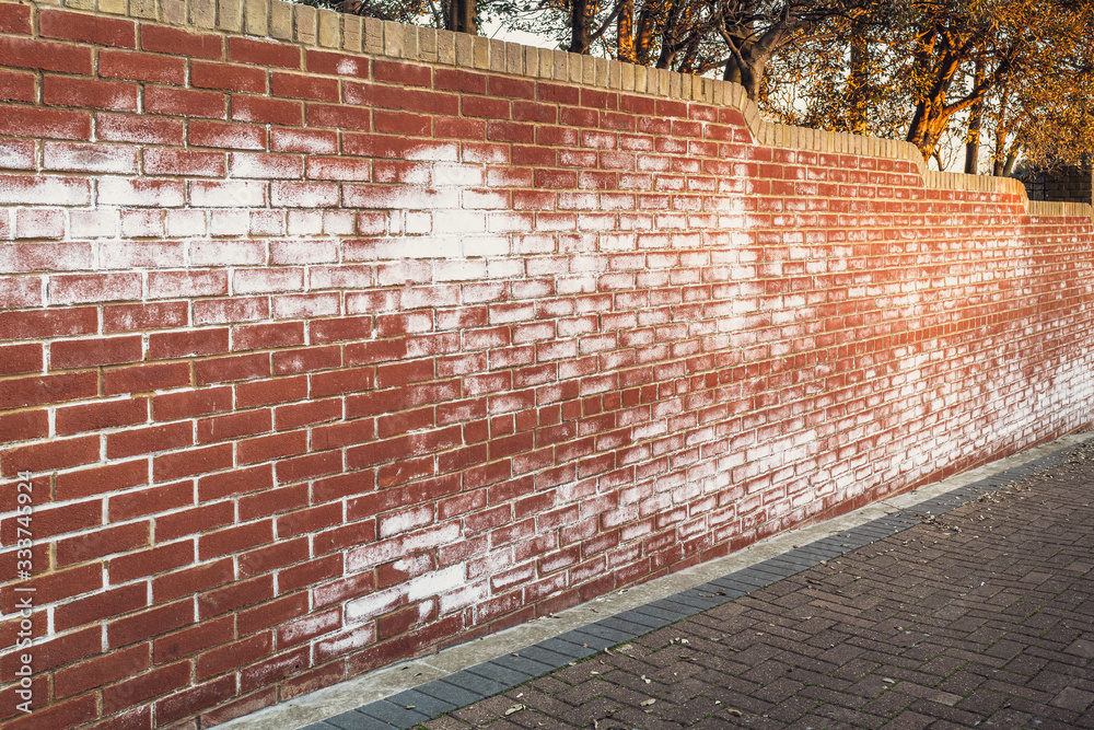 A long red brick wall stained with white efflorescence, a crystalline of  salt, formed due to water being present in or on the bricks. Stock Photo