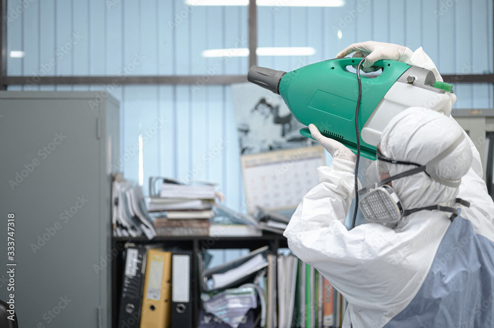 Disinfecting of office to prevent COVID-19, person in white hazmat suit with disinfect in office, coronavirus concept