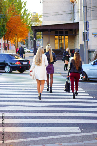 beautiful girls cross the road at an unregulated pedestrian crossing in the center of the metropolis