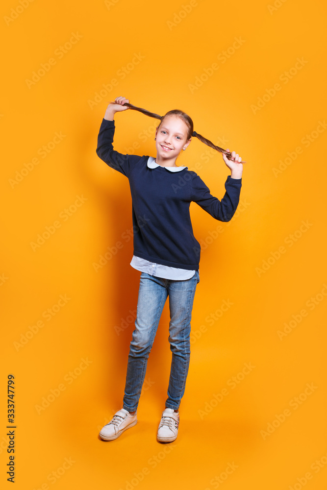 funny happy little girl in casual clothes having fun on yellow studio background funny happy little girl in casual clothes having fun on yellow studio background