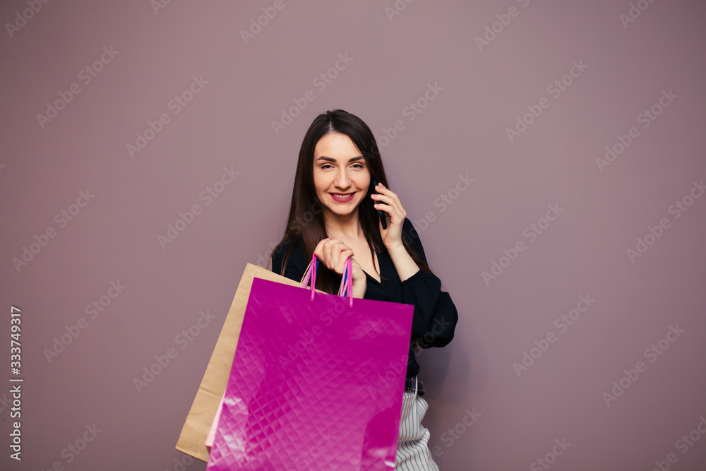 Beautiful well-dressed young girl holding a blank paper bag and shopping at an online store against a wall background with copy space for text or design. Horizontal layout Beautiful well-dressed young girl holding a blank paper bag and shopping at an online store against a wall background with copy space for text or design. Horizontal layout