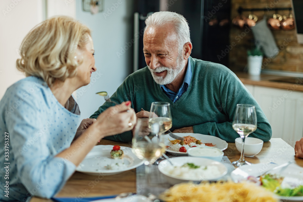 Happy senior couple enjoying in conversation while eating at dining table. Happy senior couple enjoying in conversation while eating at dining table.