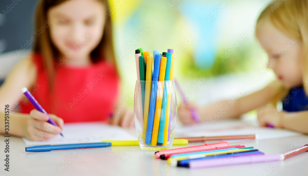 Two sisters drawing with colorful pencils at home. Creative kids doing crafts together. Education and distance learning for kids. Homeschooling during quarantine. Stay at home entertainment. Two sisters drawing with colorful pencils at home. Creative kids doing crafts together. Education and distance learning for kids. Homeschooling during quarantine. Stay at home entertainment.