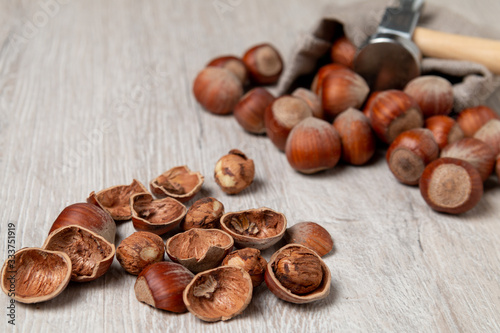 Cracked hazelnuts on a white table and hammer in the background