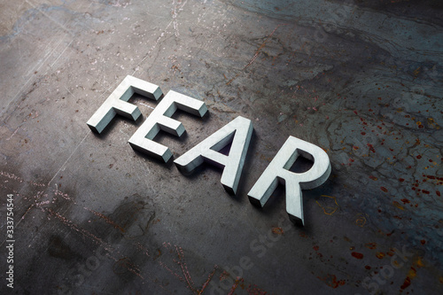 the word fear laid with silver letters on raw rusted steel sheet surface in diagonal slanted composition photo